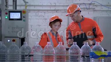 在塑料瓶装矿泉水的输送线附近，工程师将男女装在头盔和工作服上
